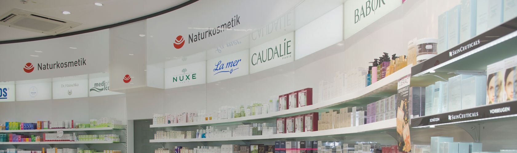 Regale einer Apotheke zeigen Naturkosmetikprodukte von Marken wie Nuxe und Caudalie.