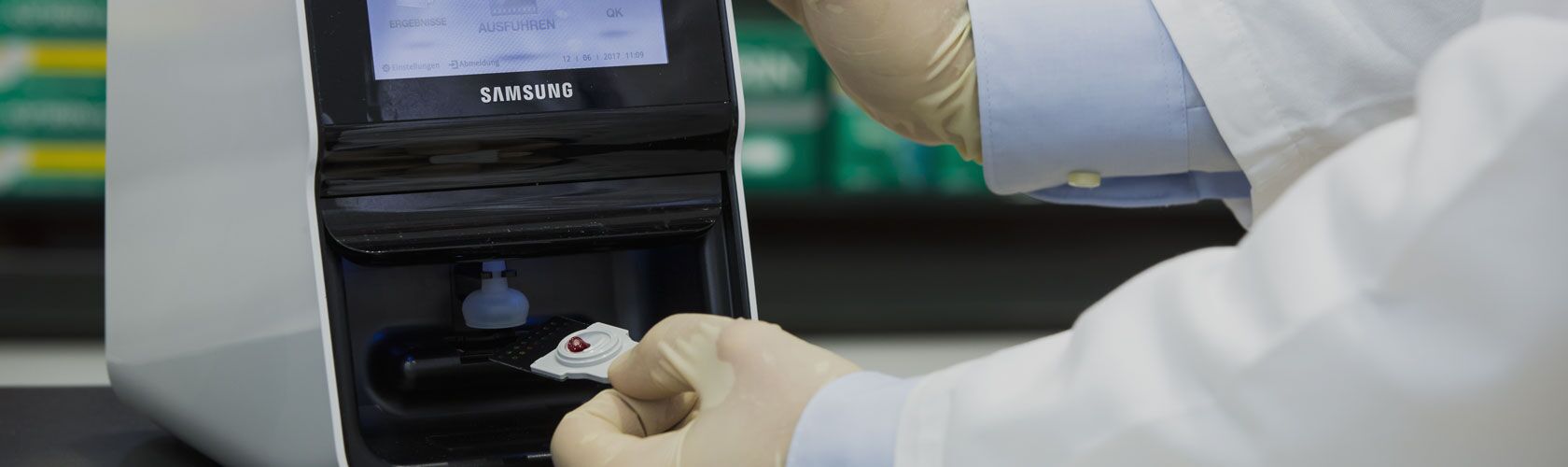 Ein Labortechniker führt eine Blutuntersuchung in einer Apotheke durch, indem er eine Probe in ein Analysegerät einlegt.
