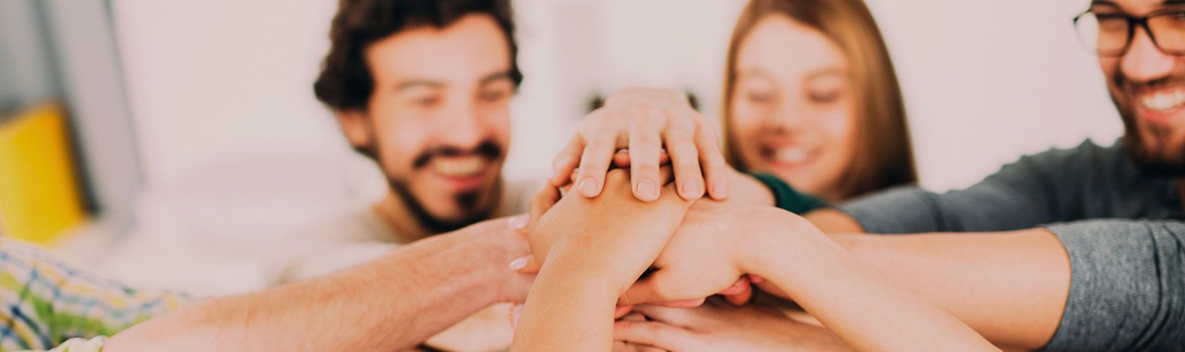 Teammitglieder stapeln freudig Hände in einer Geste der Einheit, die Zusammenarbeit und Karrierewachstum symbolisiert.